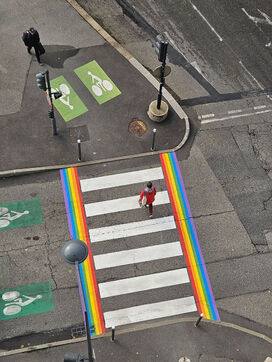 Un passage piéton bordé de bandes de peintures couleurs arc-en-ciel vue du ciel